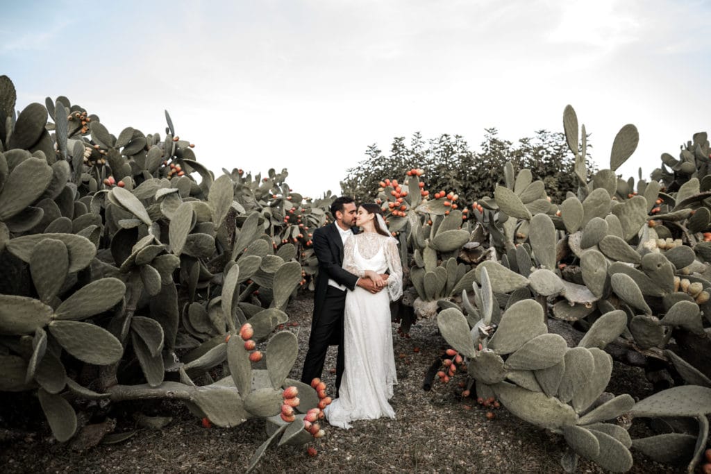 Bride and groom amidst cacti at Masseria Potenti for wedding in Puglia