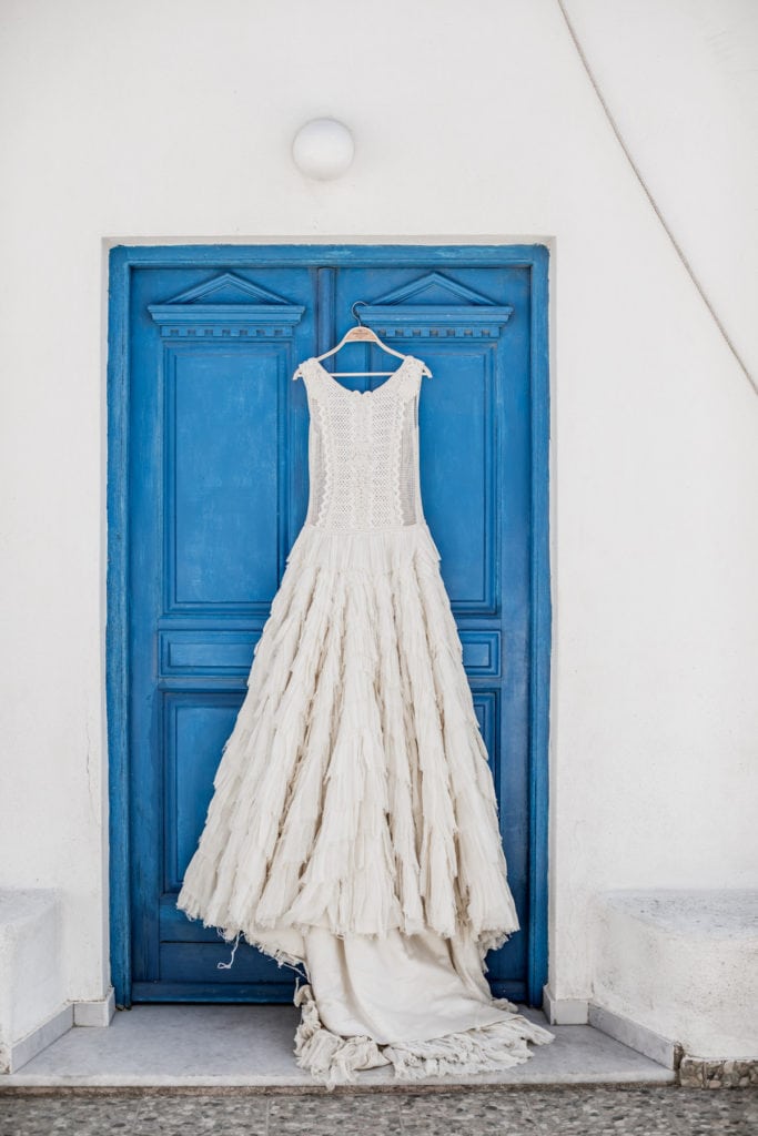 Bridal gown hanging against blue door of Greece villa