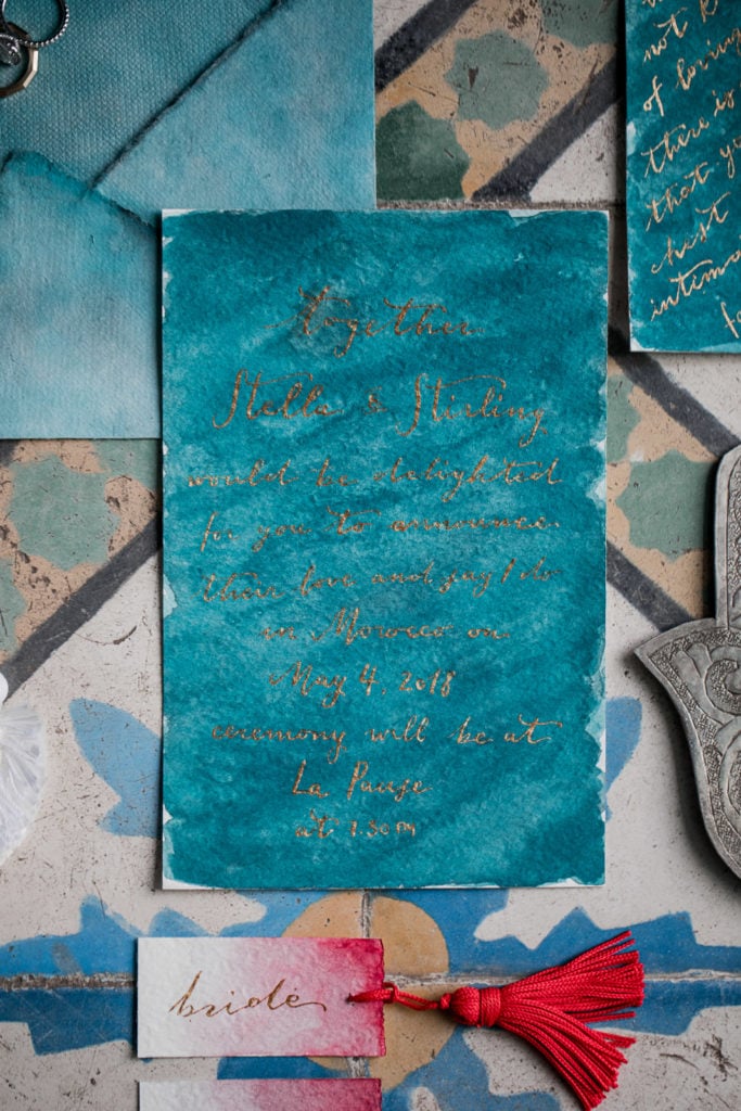 Turquoise invitation suite flat lay for Marrakech wedding
