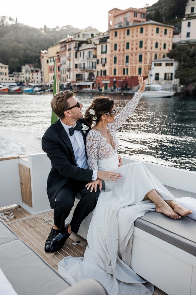 Bride and groom sit on boat in Portofino together