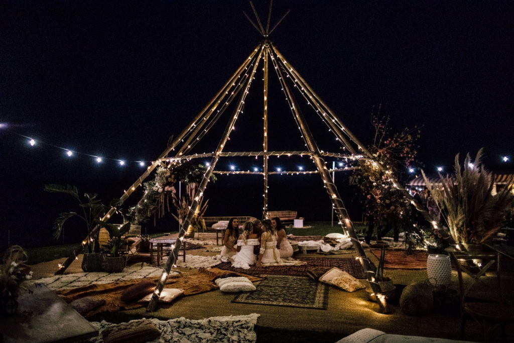 A wedding reception teepee is lit up with string lights at night