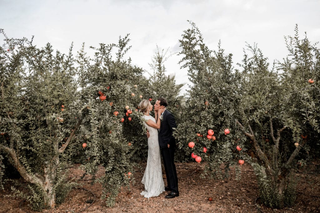 Bride and groom embrace among pomegranate grove for Mallorca wedding