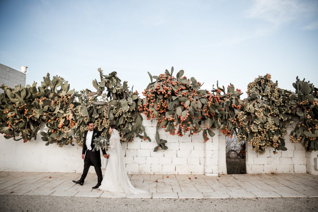 Bride and groom walk on sidewalk at Masseria Potenti after wedding in Puglia, Italy
