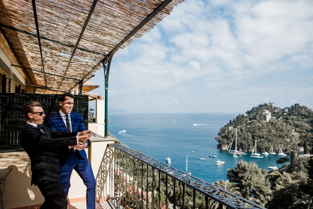 Groom and groomsmen pop champagne on balcony of Belmond Splendido before Portofino hotel wedding