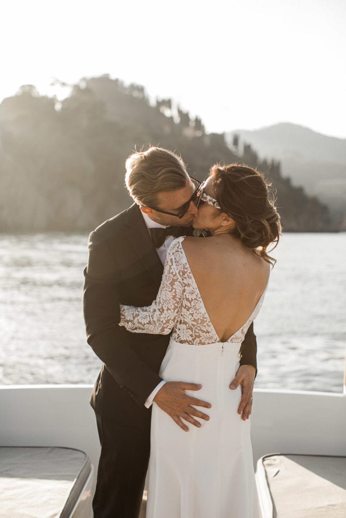 Bride and groom kiss during sunset portraits on a boat in Portofino, Italy