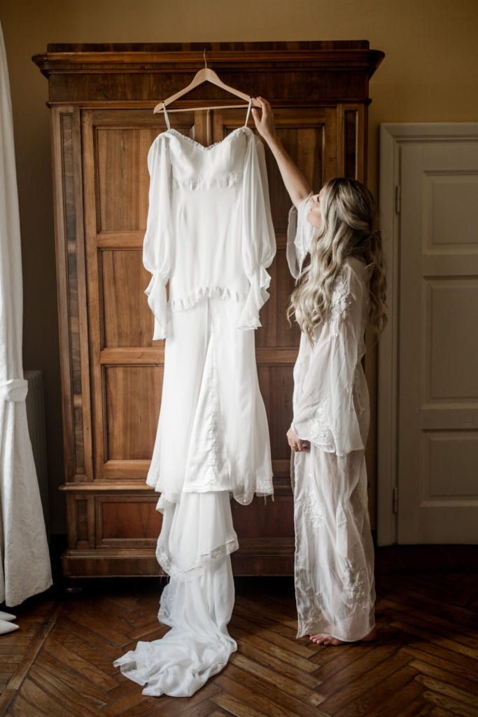 Bride pulls her bridal gown off the hanger to get ready for Lake Como wedding ceremony
