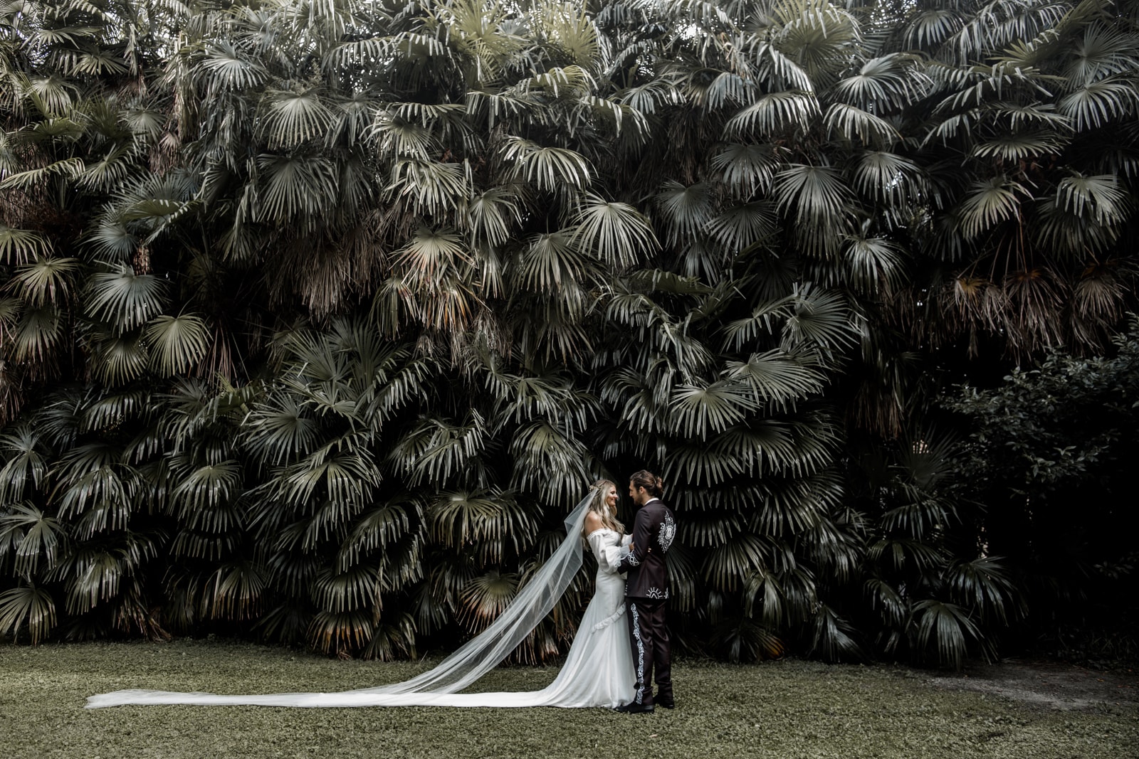 Bride and groom embrace in front of botanical wall at Giardini del Merlo for first look