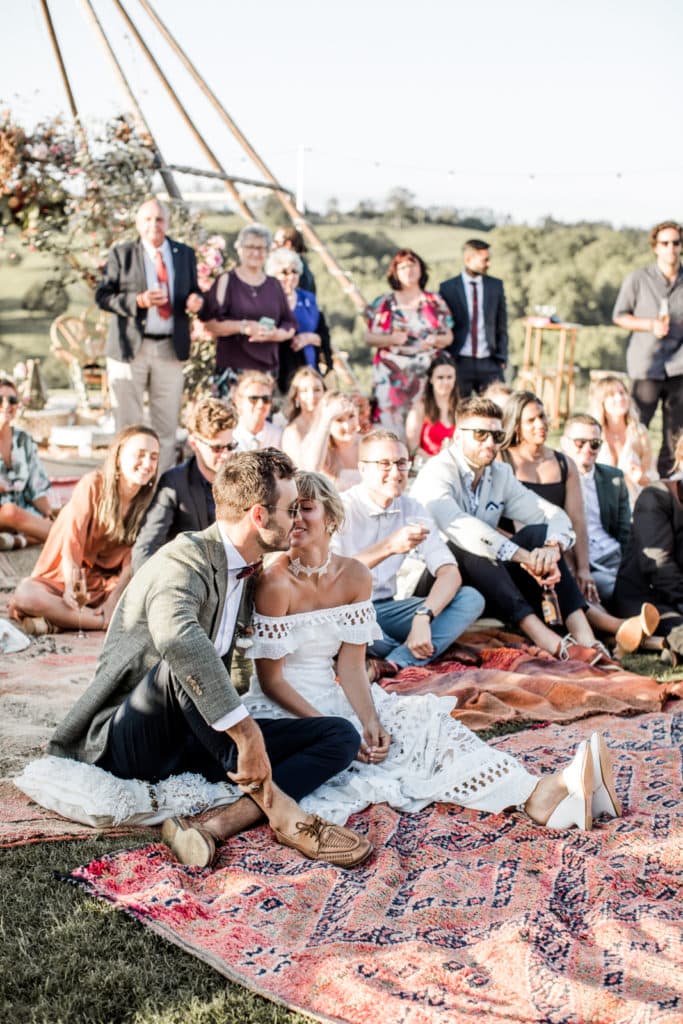 Bride and groom sit together with guests at their bohemian-chic, destination Australia wedding reception