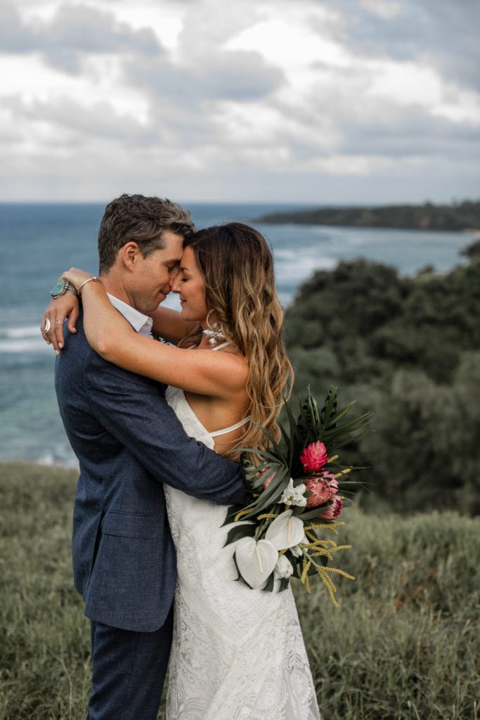 Bride and groom embrace during couple's portraits overlooking the Hawaiian coast