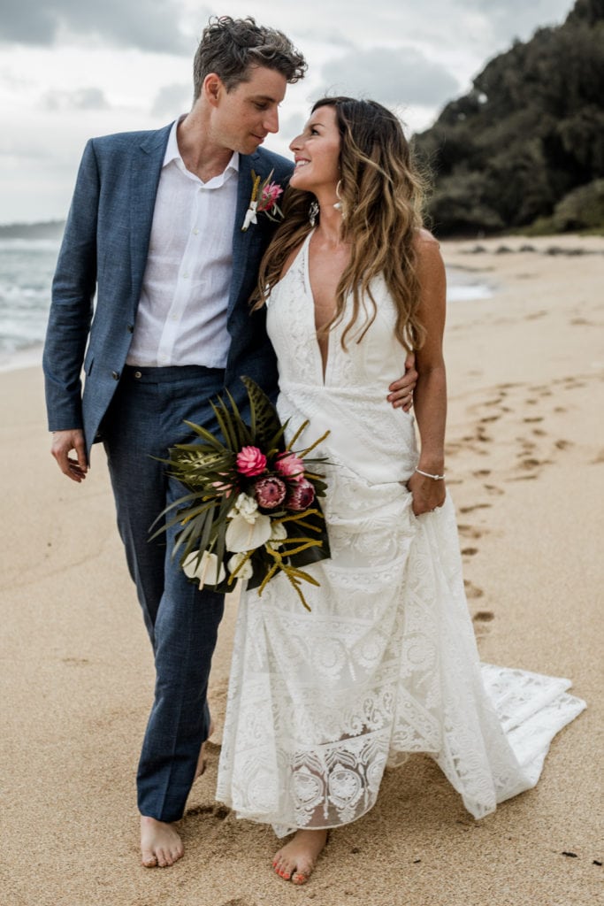 Bride and groom walk together on sandy beach after Kauai, Hawaii wedding