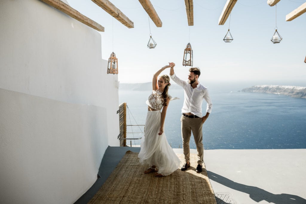 Bride and groom dance on their private balcony overlooking the ocean in Santorini