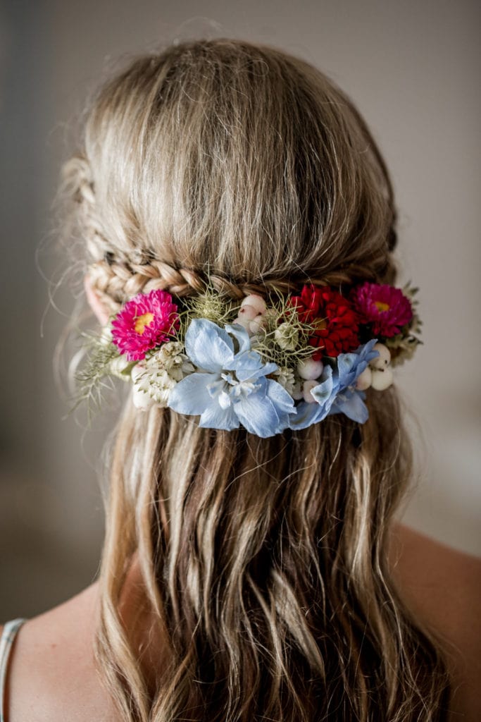 Bride wears hair in braids with floral accessories for wedding ceremony