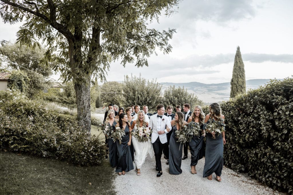 Bride and groom and their wedding party walk to the wedding reception at Borgo di Castelvecchio in Tuscany, Italy