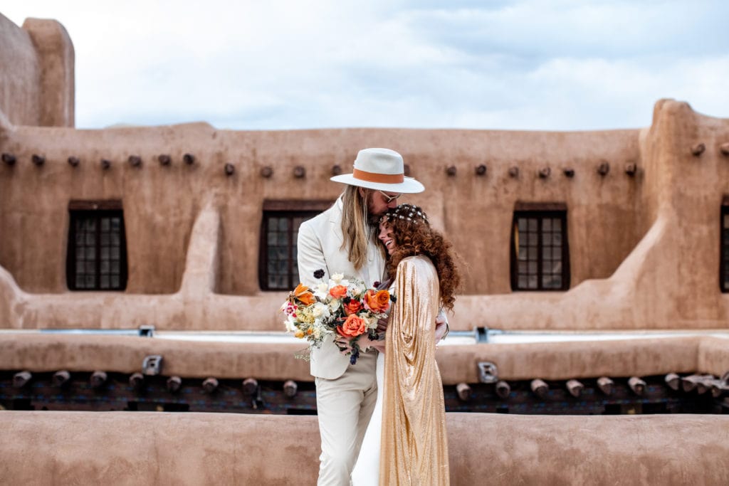 Bride and groom embrace in front of New Mexico Museum of Art after their wedding ceremony