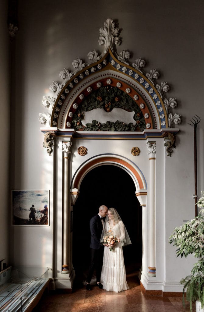 Bride and groom stand in archway at Vajdahunyad Castle for destination Budapest wedding