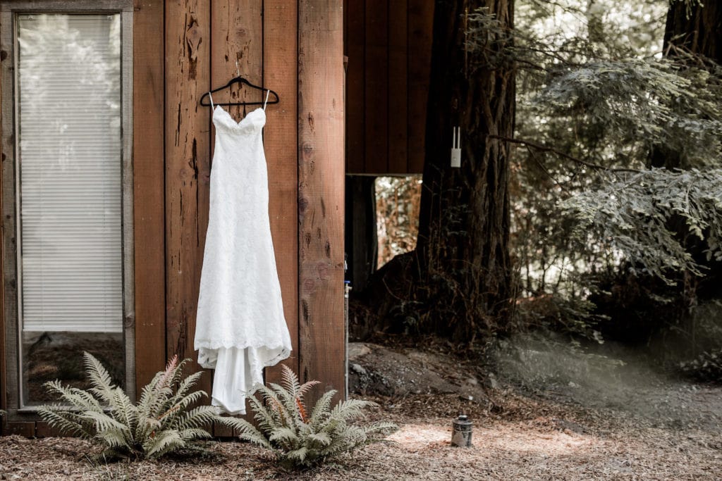 Bridal gown hangs from cabin wall at Glen Oaks, Big Sur wedding venue