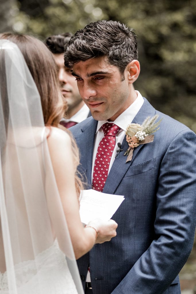 Groom looks at bride during wedding ceremony in Big Sur, California