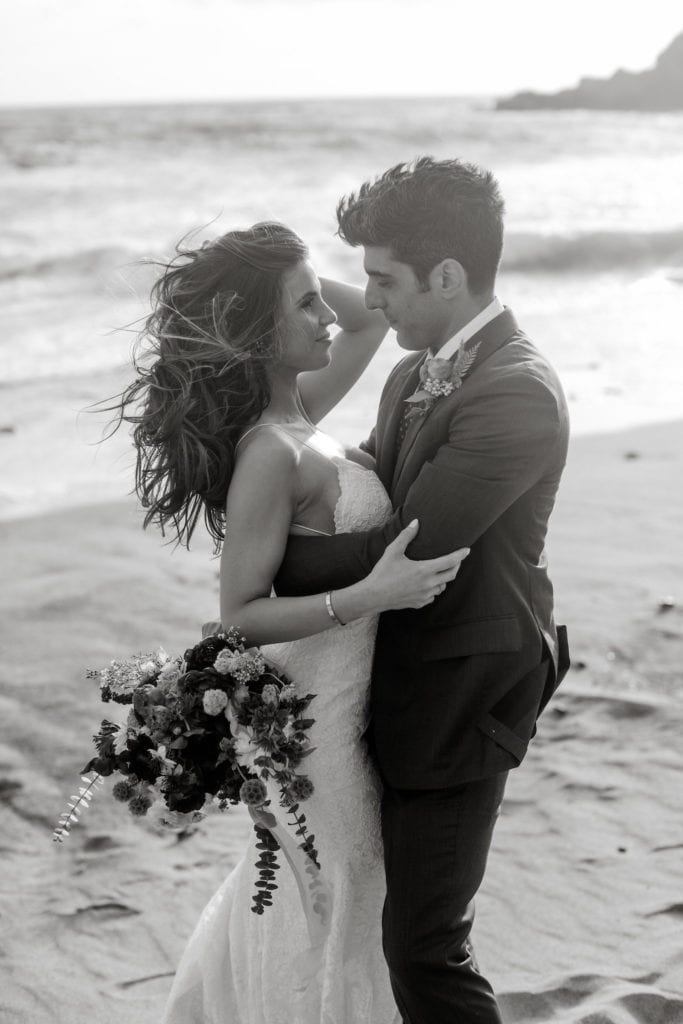 Bride and groom embrace during couple's portraits on Big Sur, California beach