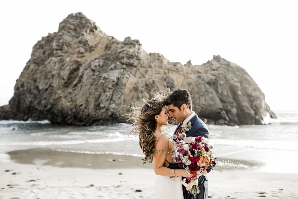 Bride and groom pose for couple's portraits on California beach after Big Sur wedding