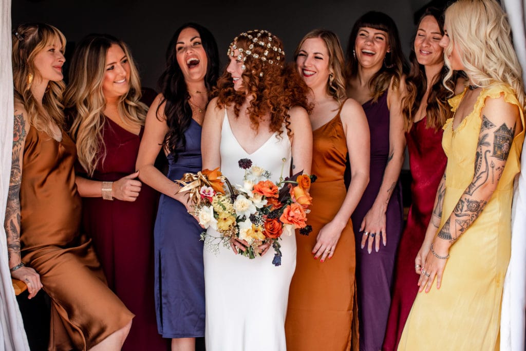 Bride stands with bridesmaids as they wear their bridesmaids dresses inspired by southwestern colors