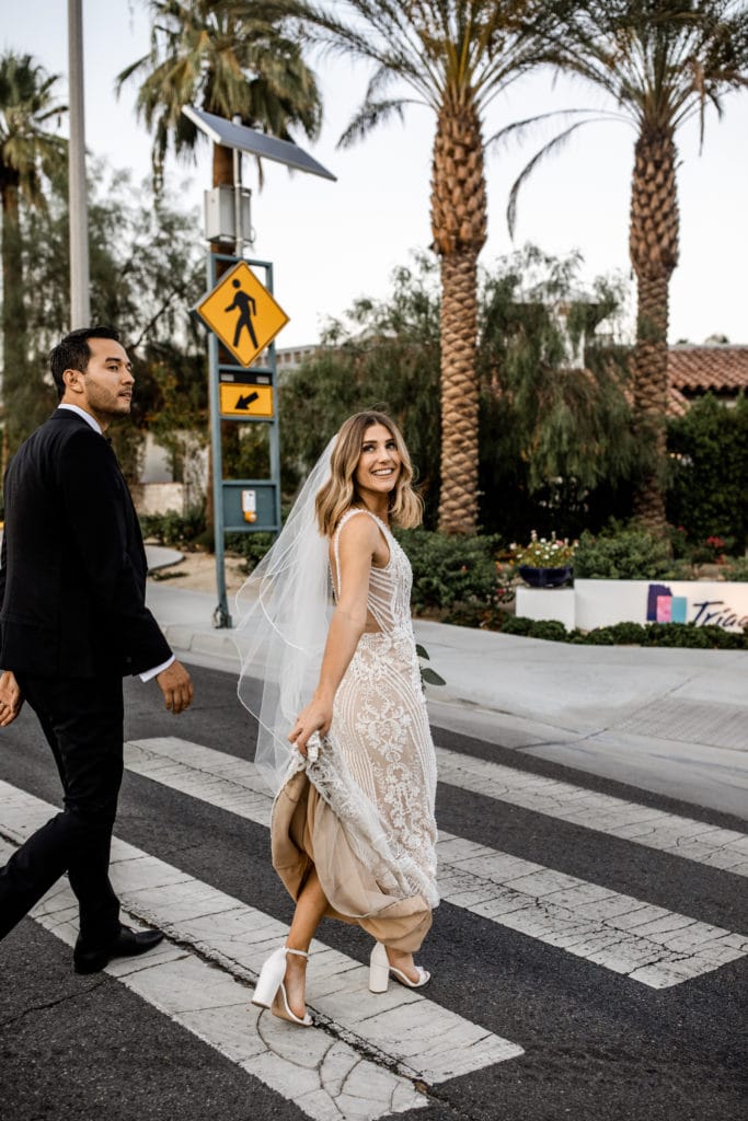 Bride and groom walk across street in downtown Palm Springs