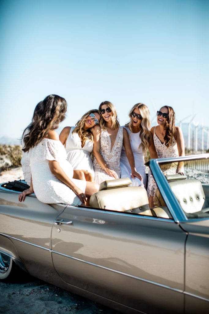 Bride and bridesmaids in back of classic cadillac convertible