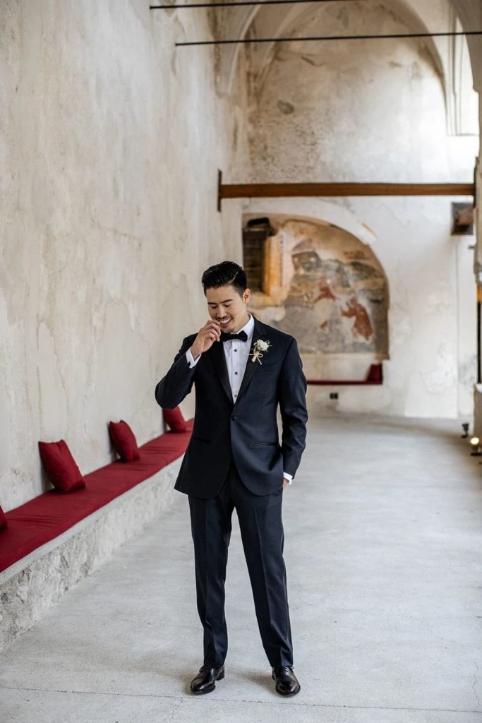 Groom, wearing groom wedding attire ideas, stands in Grand Hotel Convento waiting for bride during first look
