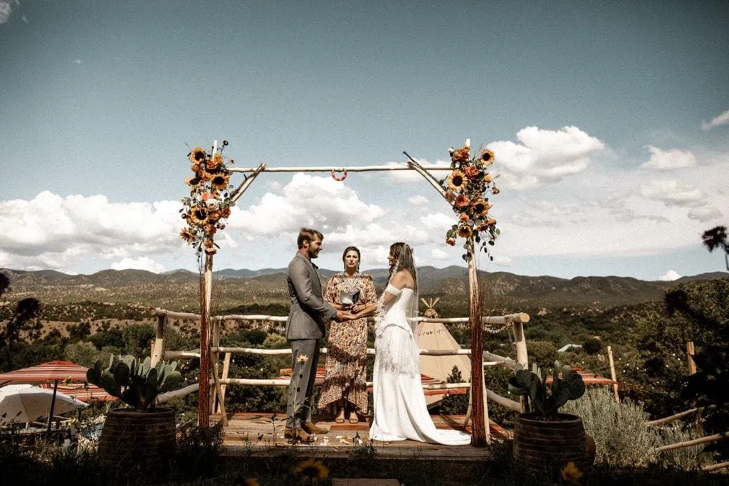 Bride and groom stand at outdoor wedding ceremony altar in Santa Fe New Mexico with view of mountains in background