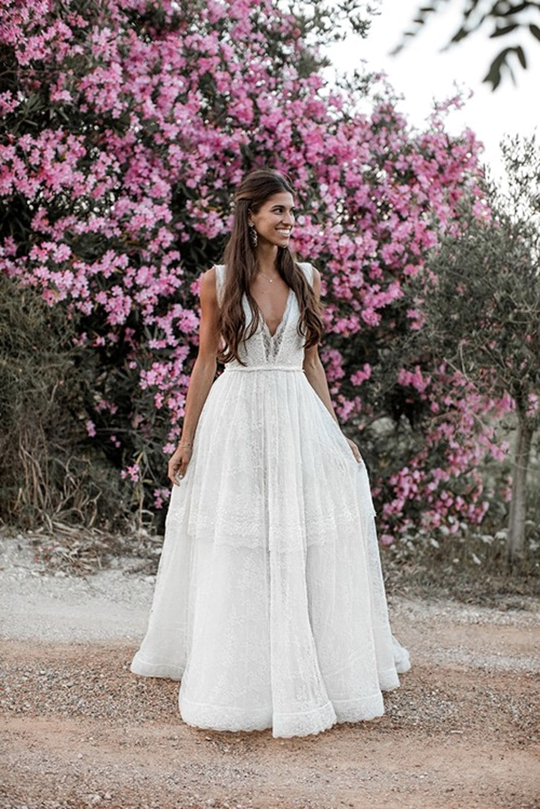 Bride stands in wedding gown in front of vibrant pink flowers in Ibiza Spain