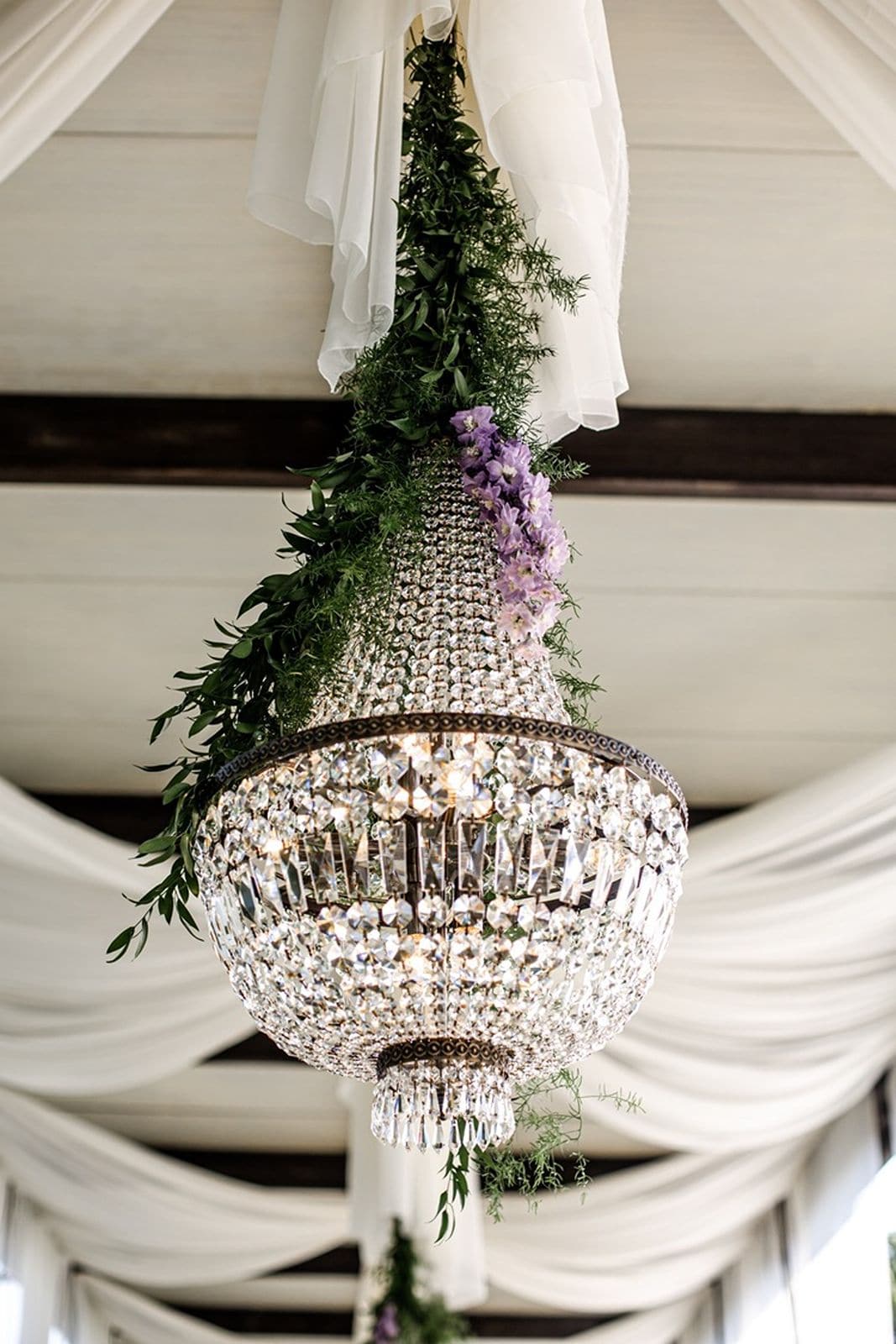 Chandelier hangs down from tented wedding ceremony setup