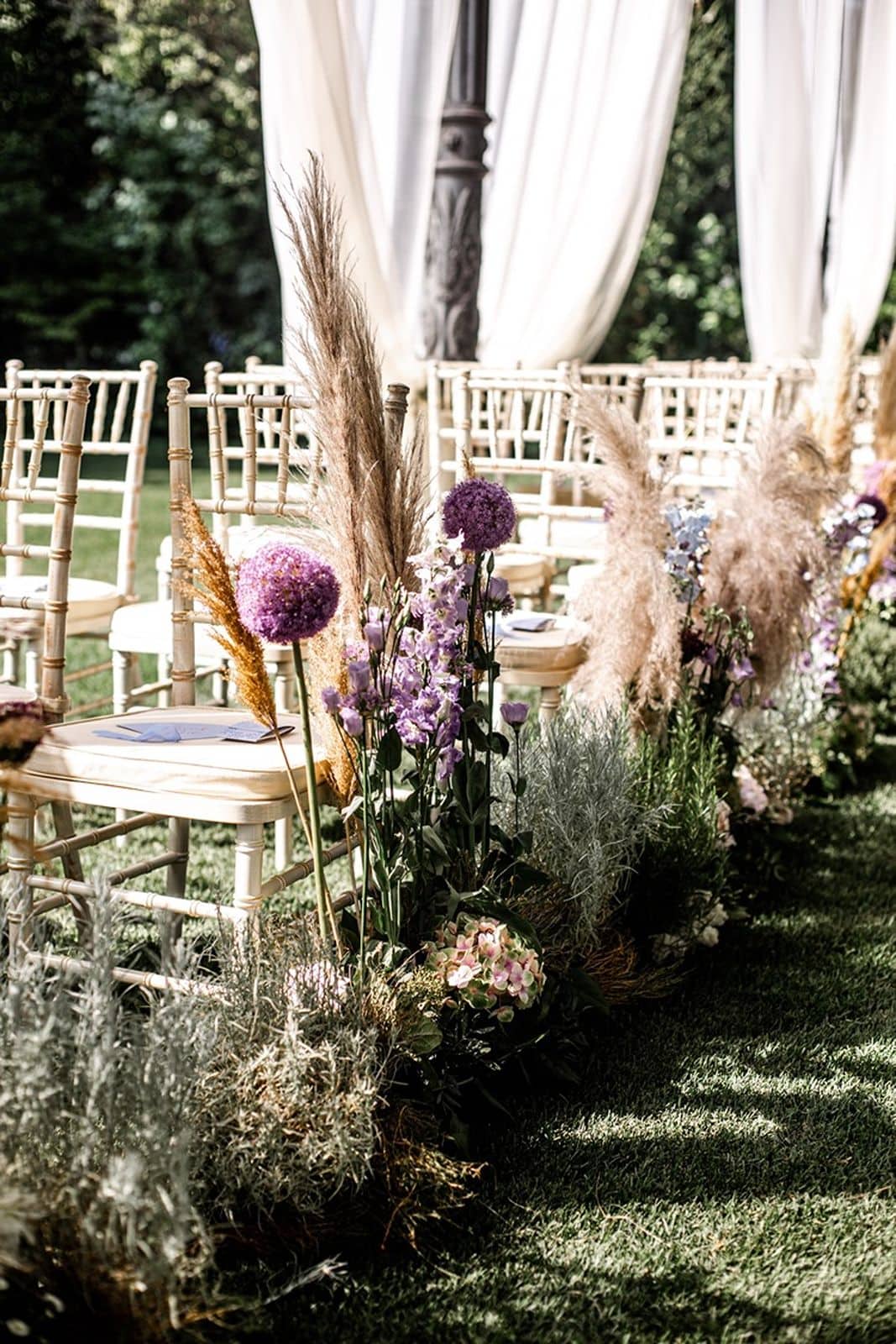 Wedding ceremony guest seating surrounded by aisle marker floral arrangements
