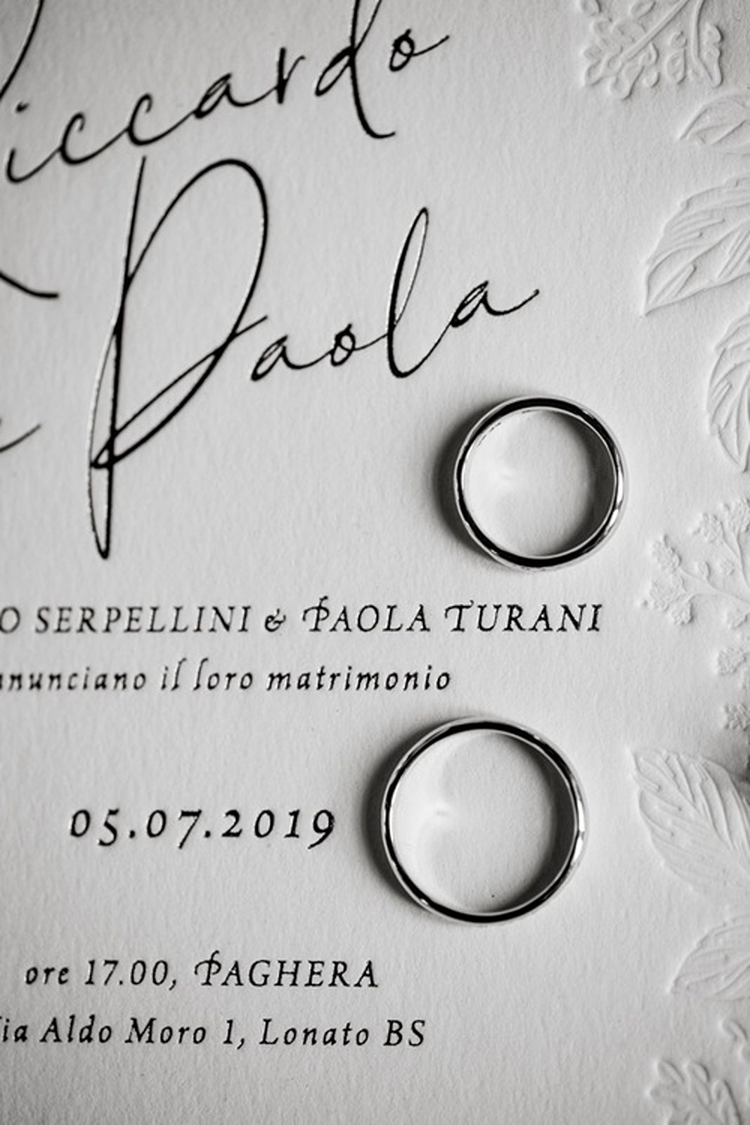 Two wedding bands rest on invitation card