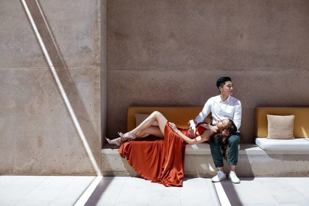Woman wearing red dress lays her head on lap of a man at Amangiri