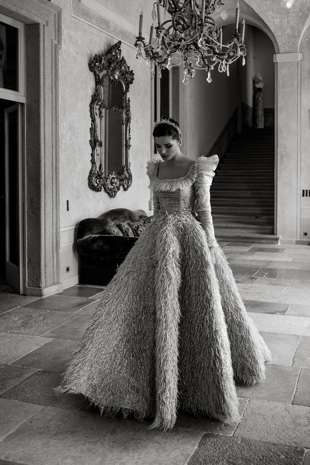 Bride wearing a feather-skirted bridal gown walks halls of Villa Balbiano