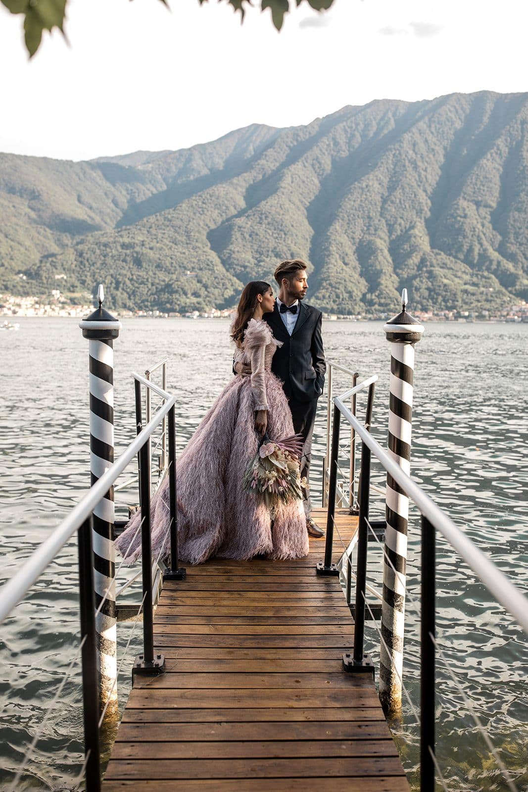 Bride and groom stand on a dock at Lake Como after elopement ceremony