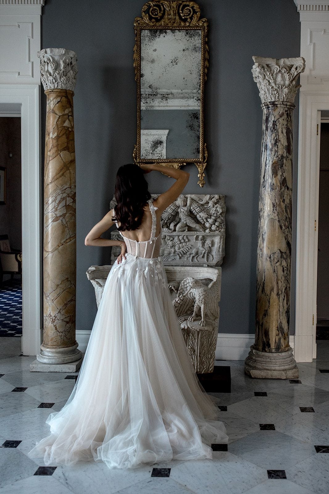 Bride stands in Villa Astor among the marble columns