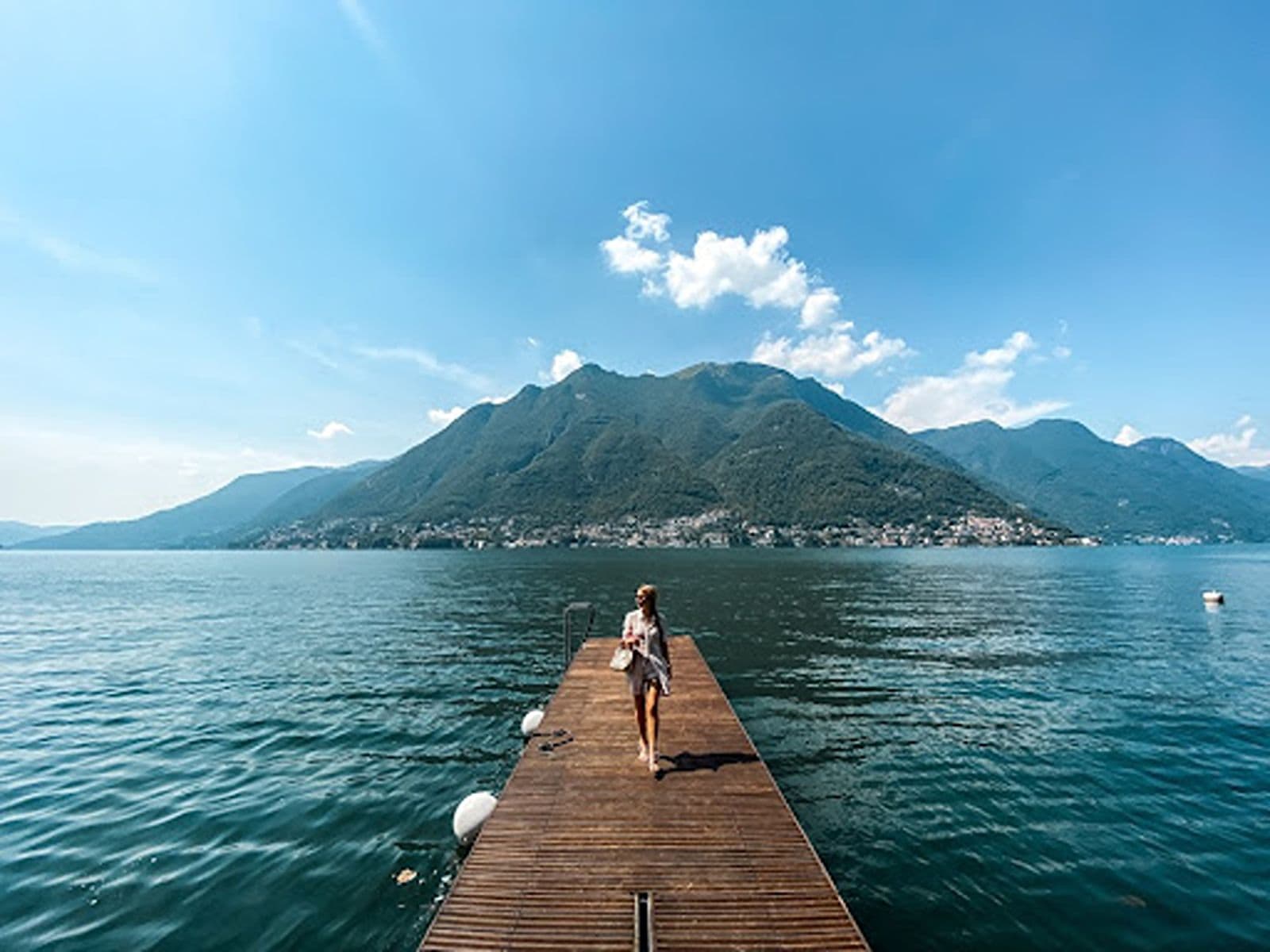 Woman walks on a dock near Lake Como to showcase best unique things to do in Lake Como