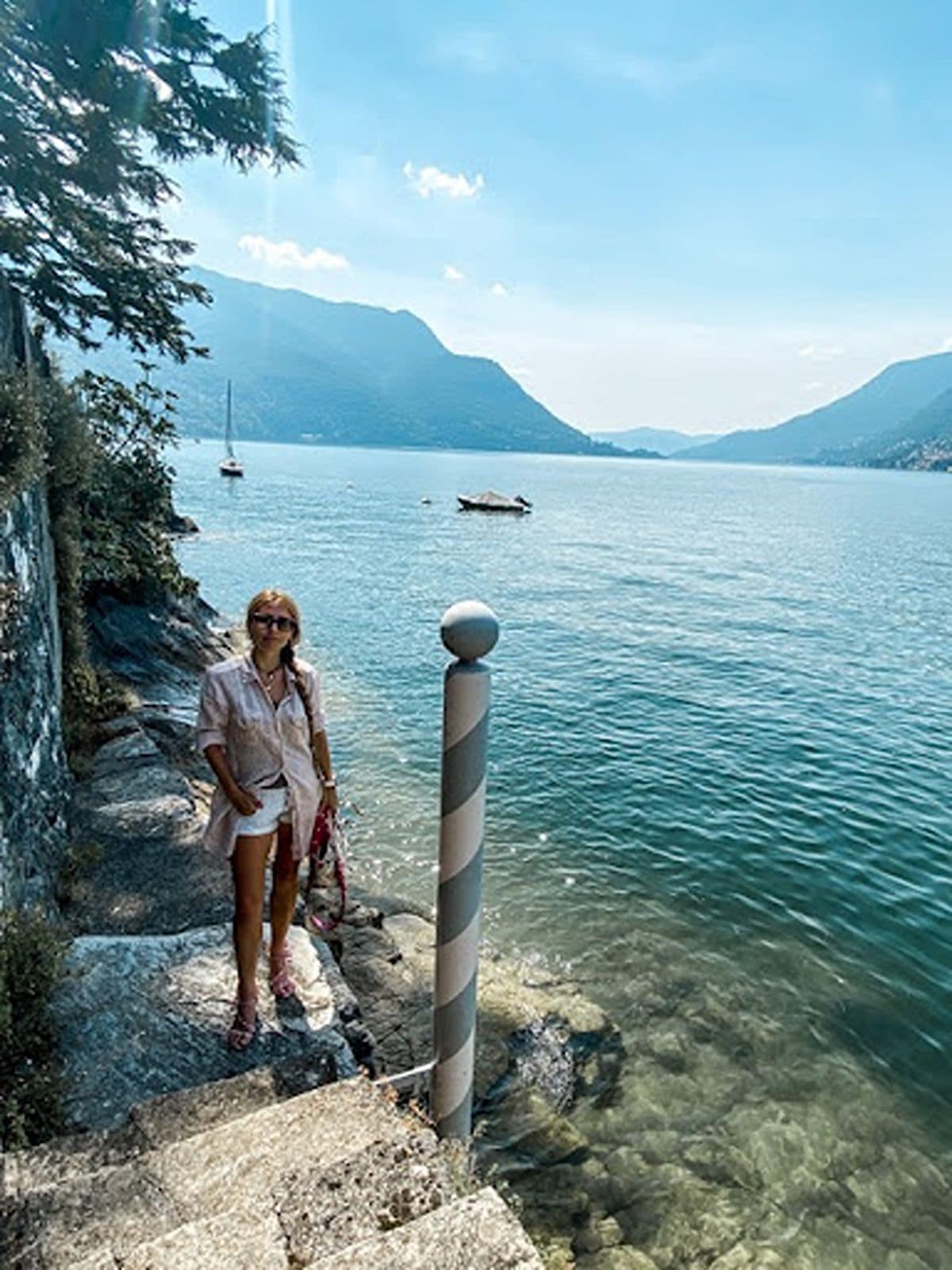 Woman stands on steps at Lake Como water's edge