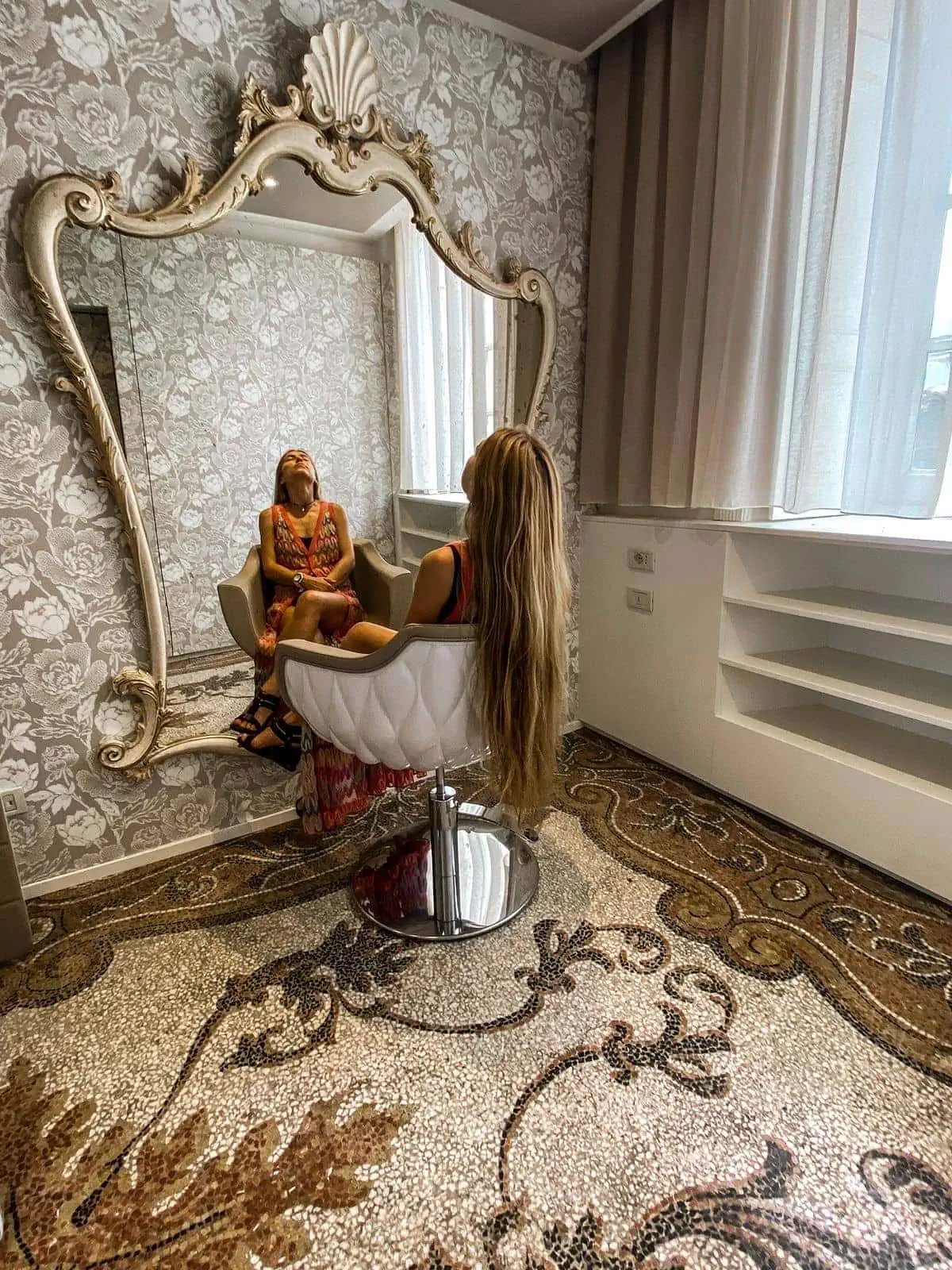 Woman sits in a chair in front of an ornate mirror in Grand Hotel Tremezzo, one of the best places to stay in Lake Como