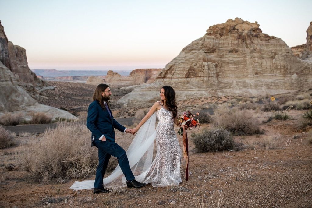 Bride and groom walk through desert landscape in Utah