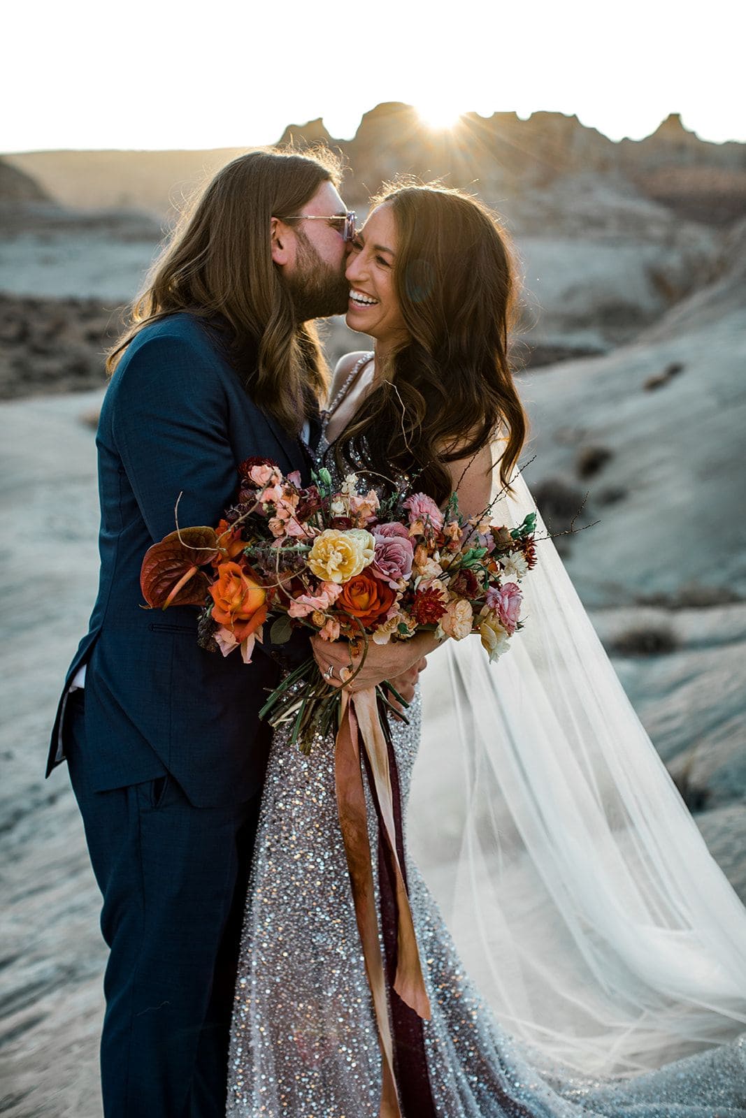 Groom kisses bride's cheek in Utah desert