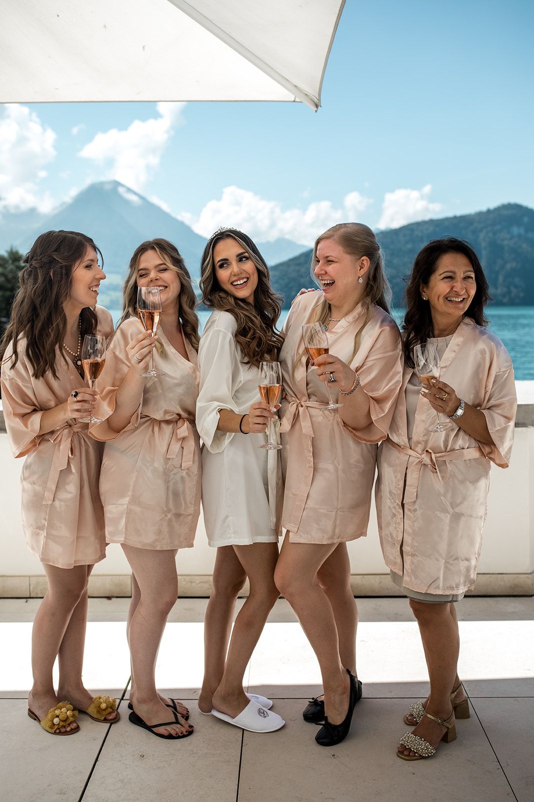 Bride and bridesmaids on a balcony sharing aperitif before Lake Lucerne wedding ceremony