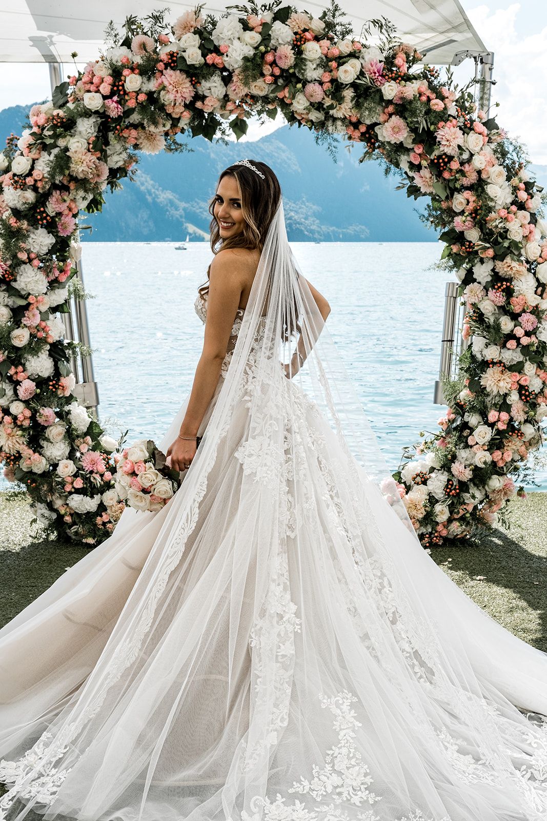 Bride stands in Galia Lahav wedding gown at floral ceremony arch for Switzerland destination wedding