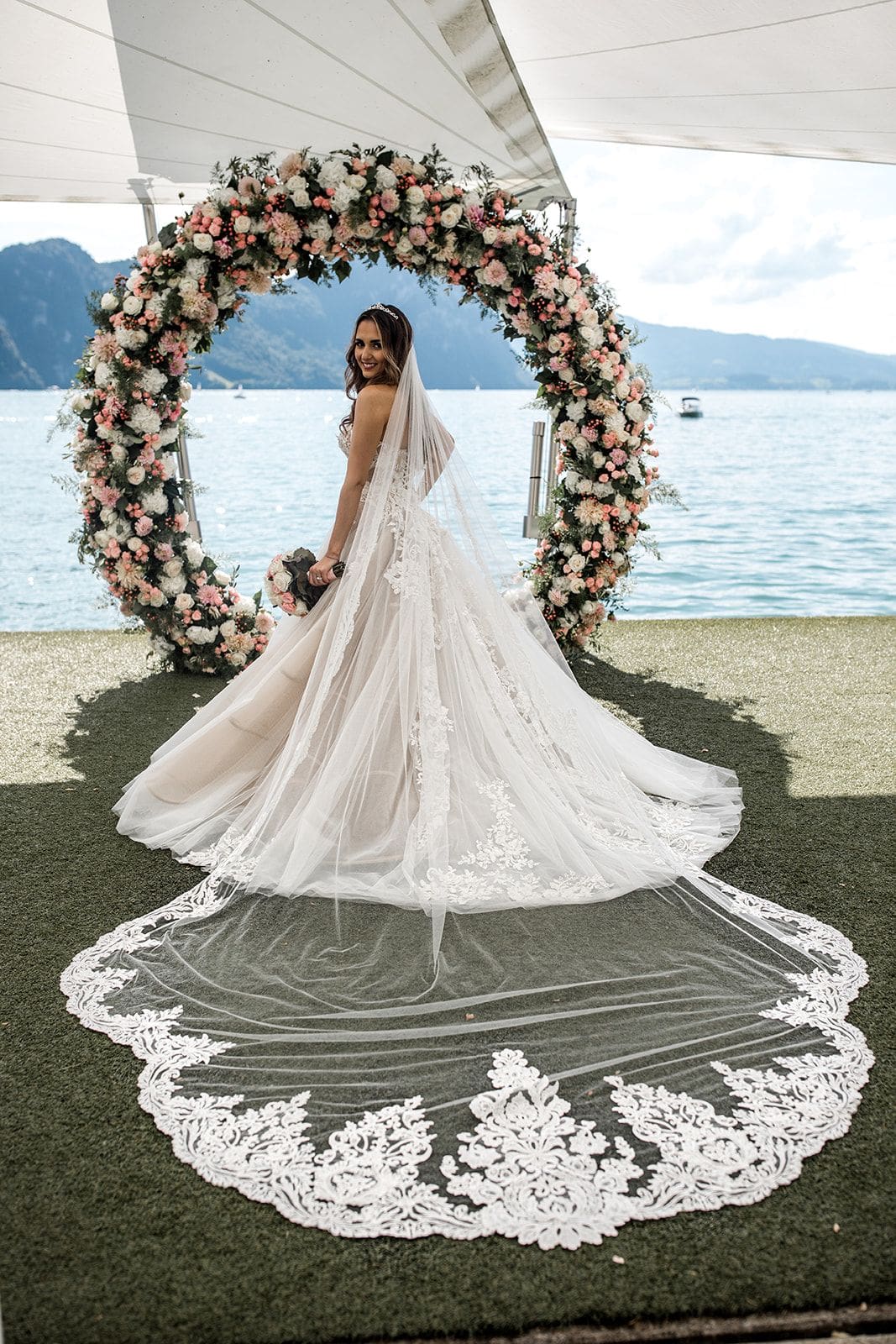 Bride stands at floral ceremony arch overlooking Lake Lucerne, Switzerland