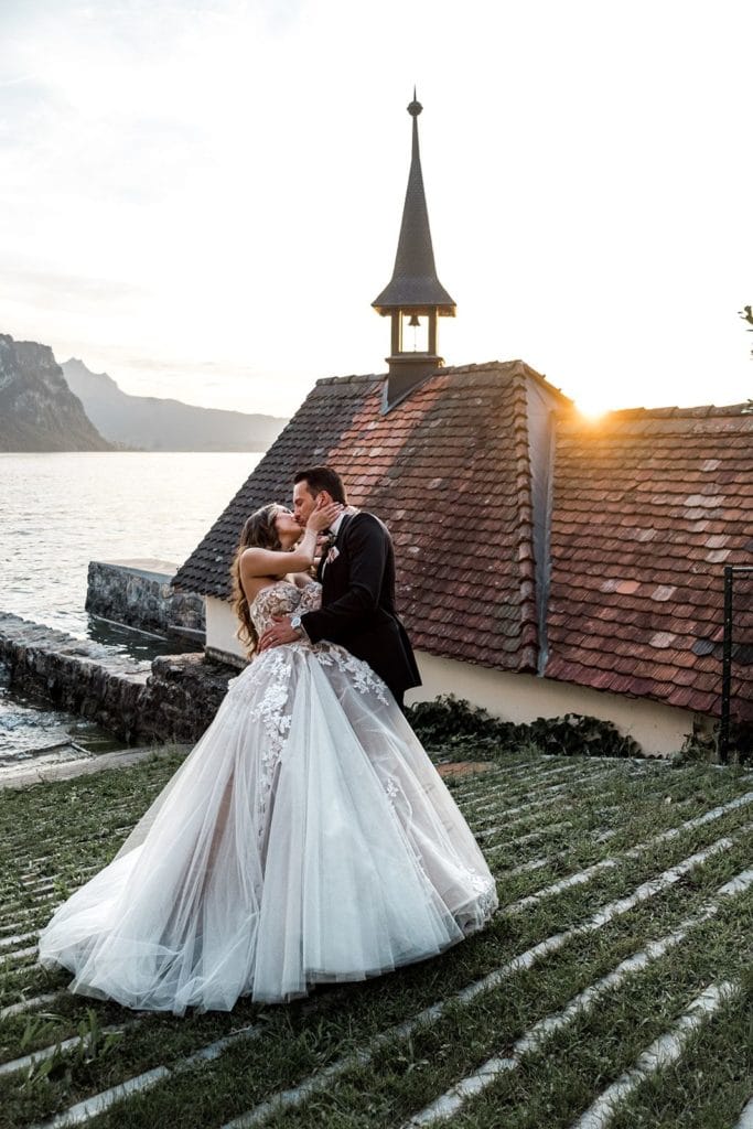 Bride and groom kiss for sunset portraits after Lake Lucerne wedding after using the right questions to ask wedding photographers when finding the perfect fit