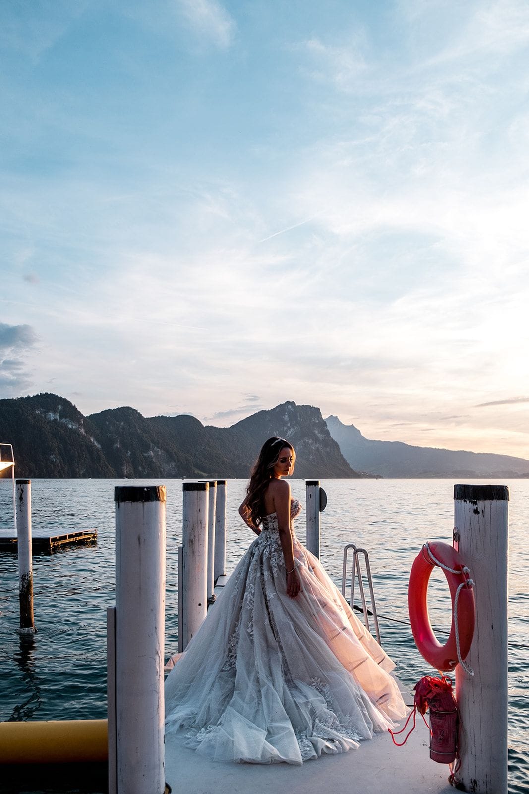 Bride on dock overlooking Lake Lucerne and Swiss mountains
