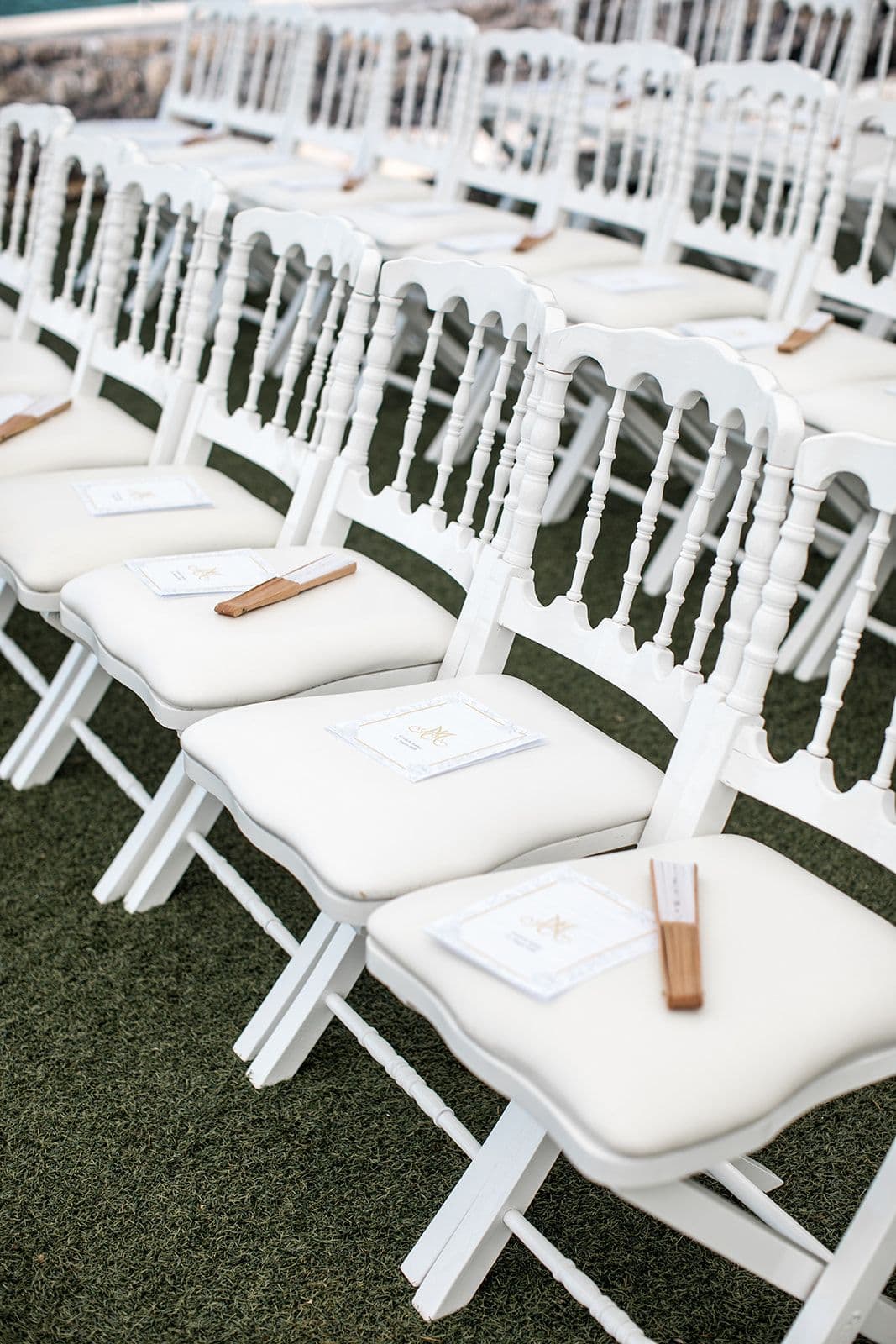 White chairs with fans for guests during wedding ceremony