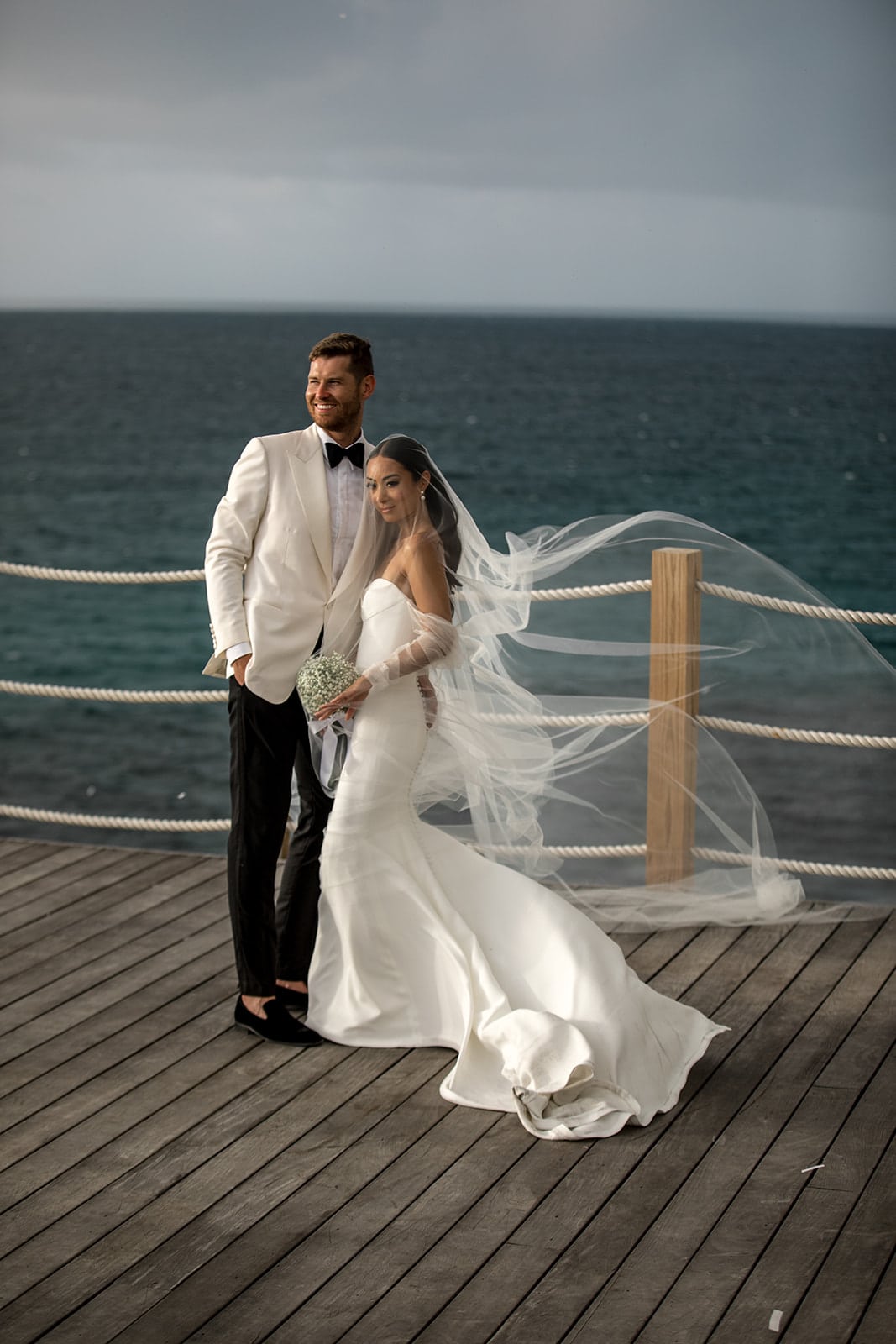 Bride and groom stand on a dock overlooking the ocean in Anguilla