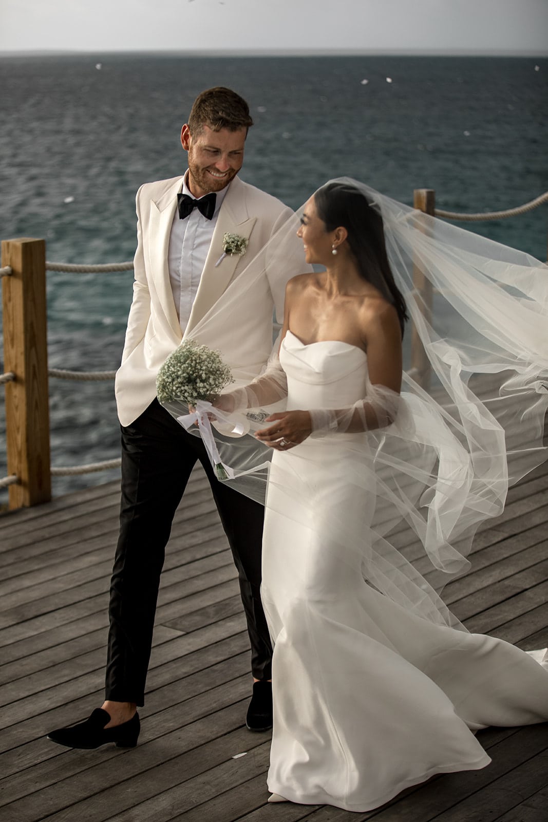 Bride and groom walk on a dock overlooking the ocean in Anguilla