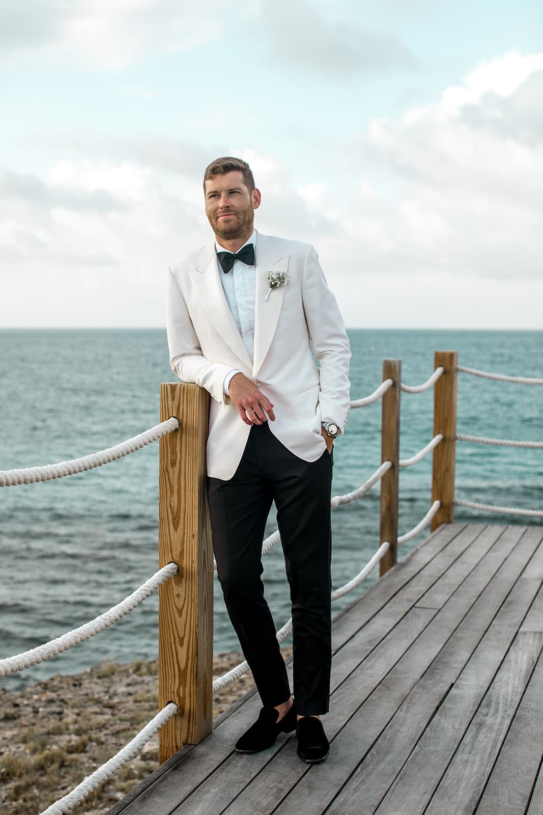 Groom stands on dock at Anguilla beach